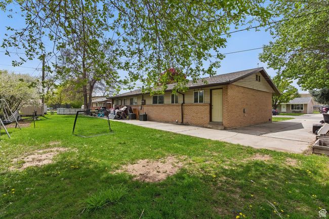 Rear view of house with brick siding, entry steps, a lawn, and fence | Image 30