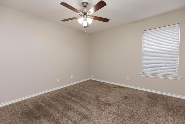 Carpeted empty room with ceiling fan and baseboards | Image 13