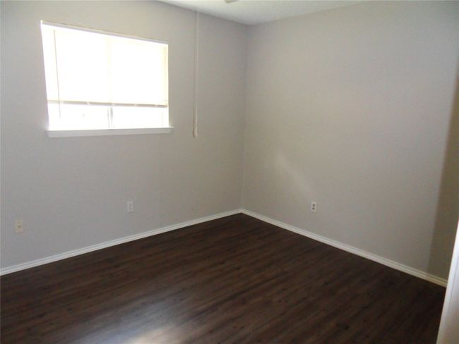 Spare room with dark wood-type flooring, baseboards, and ceiling fan | Image 9