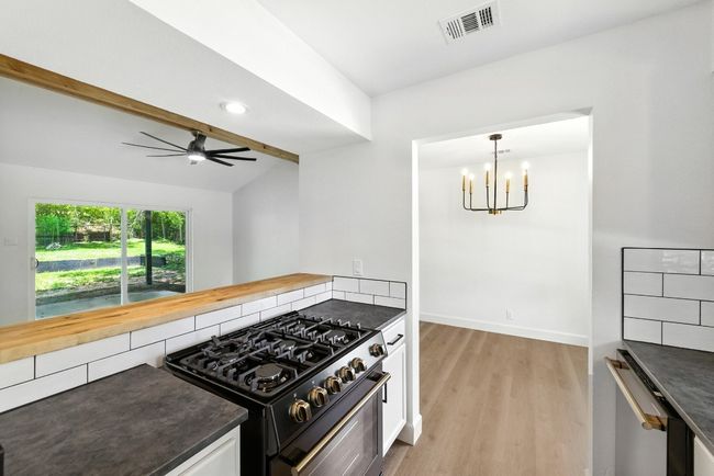 Kitchen featuring gas stove, light wood-style flooring, a chandelier, dishwasher, and ceiling fan | Image 13