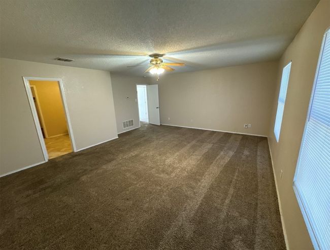 Unfurnished bedroom with ceiling fan, dark carpet, and a textured ceiling | Image 22