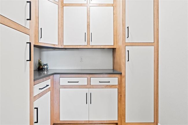 Kitchen with white fridge, dark countertops, and white cabinetry | Image 16