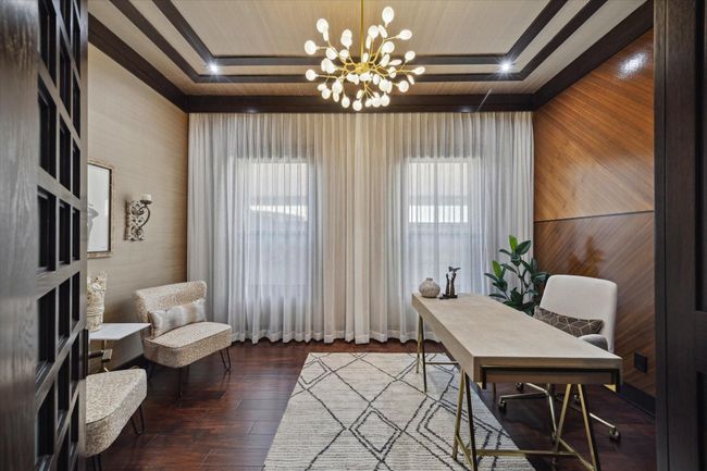 This stylish secondary office offers a refined and tranquil setting, featuring a dramatic contemporary chandelier, wood-trimmed tray ceiling with inlaid lighting, imported European silk wall coverings, and richly toned hardwood flooring. Soft sheers filter natural light through double windows, while a sleek desk and chic seating area create a comfortable space for reading, working, or quiet reflection. A perfect blend of calm, class, and contemporary flair. | Image 23