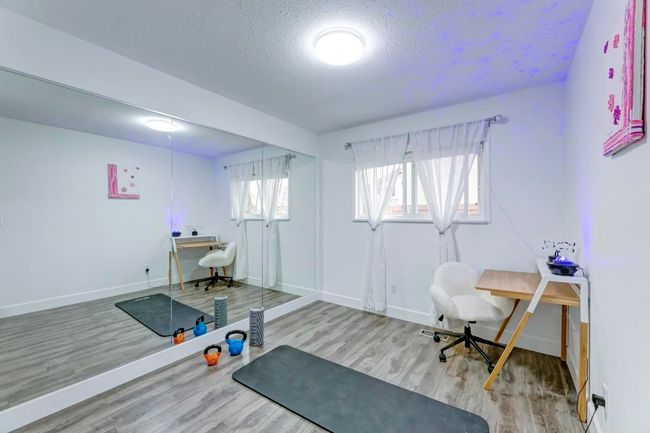 Office area with wood finished floors, a textured ceiling, and baseboards | Image 13