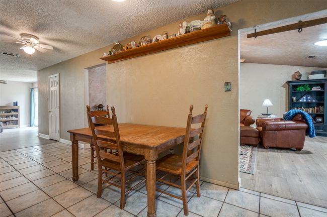 Dining room featuring a textured wall, ceiling fan, a textured ceiling, light tile patterned floors, and visible vents | Image 13