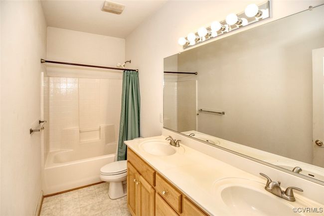 Bathroom with shower / tub combo with curtain, a sink, double vanity, and toilet | Image 27