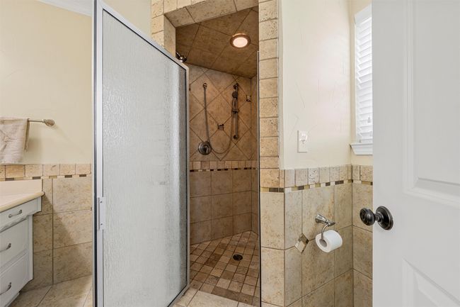 Bathroom featuring a stall shower, tile walls, vanity, and a wainscoted wall | Image 19