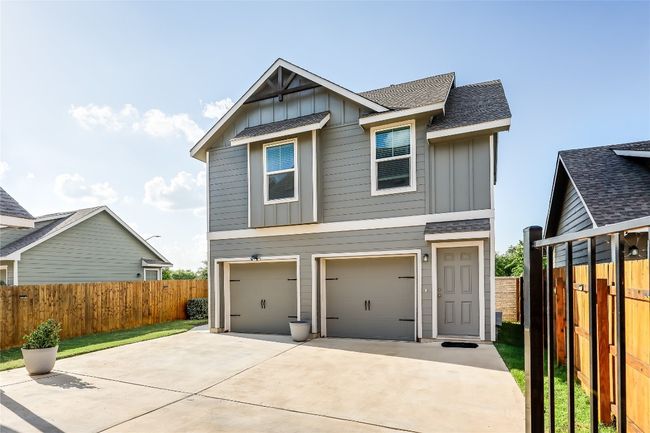 View of front of garage & garage apartment with board and batten siding, roof with shingles & concrete driveway | Image 28