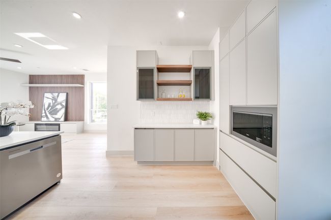 Kitchen featuring stainless steel dishwasher, light hardwood / wood-style flooring, white cabinetry, and tasteful backsplash | Image 16