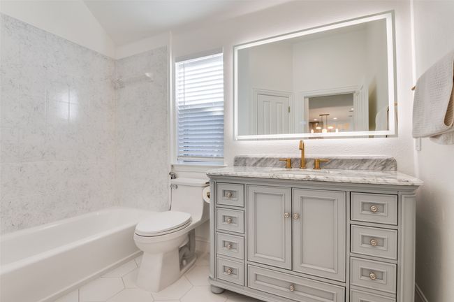 Full bathroom featuring tile patterned flooring, vanity, lofted ceiling, toilet, and bathing tub / shower combination | Image 12