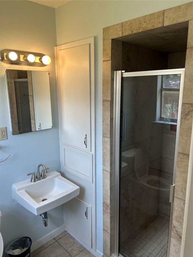 Bathroom featuring a stall shower, tile patterned floors, and a sink | Image 10