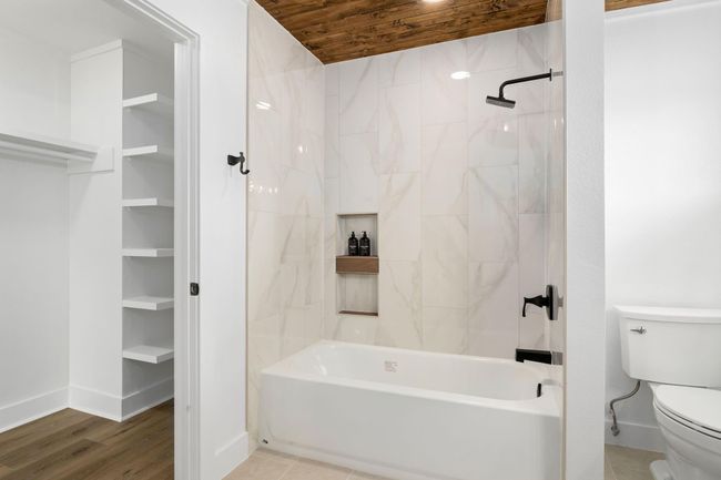Luxurious ensuite featuring a sleek tub, all new stylish fixtures, and ample storage, creating a serene retreat in the primary bedroom. | Image 23