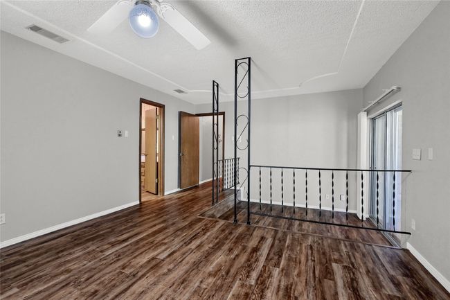 Empty room with ceiling fan, a textured ceiling, visible vents, wood finished floors, and baseboards | Image 29
