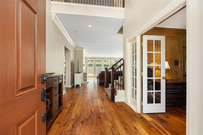 From the moment you walk in, the home opens up with a sense of space and light. A French-door study sits to your right, while a view through the living room and tall windows offers a glimpse of the backyard retreat beyond. | Image 7