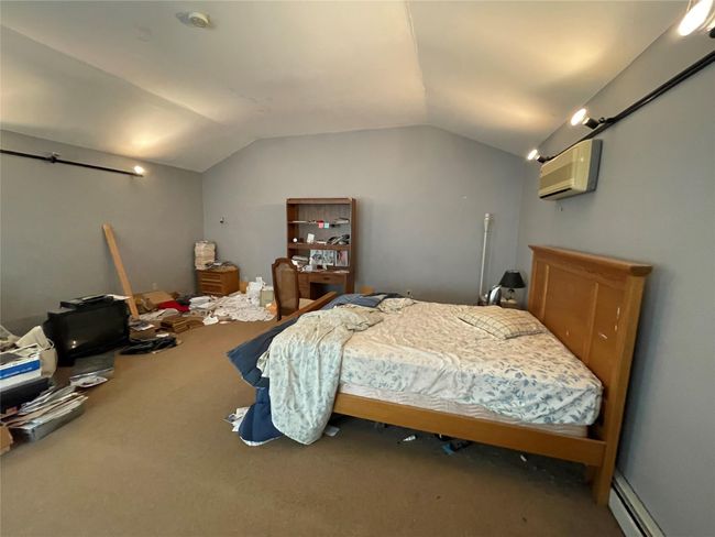 Carpeted bedroom with a baseboard radiator, a wall unit AC, and lofted ceiling | Image 9