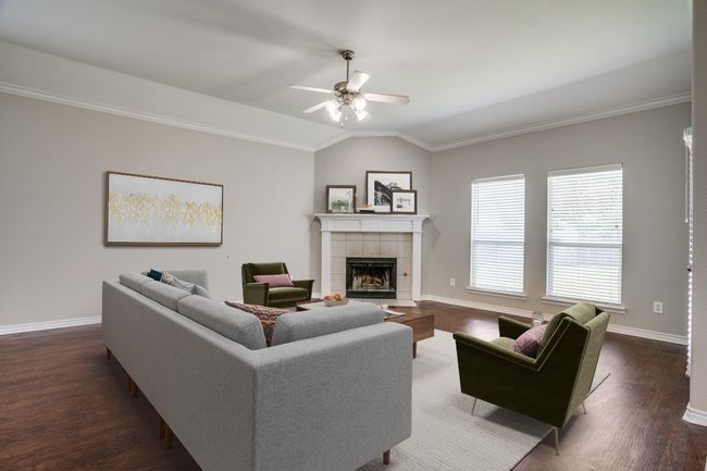 Living area featuring vaulted ceiling, a fireplace, a ceiling fan, crown molding, and baseboards | Image 4