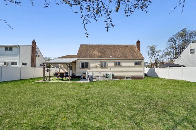 Back of property featuring a lawn, a fenced backyard, a chimney, and a patio area | Image 17