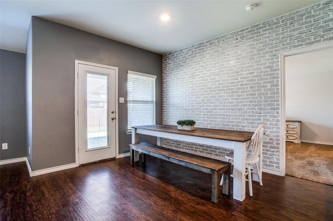 Dining room with brick wall and dark wood-type flooring | Image 12