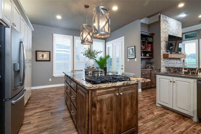 Kitchen featuring gas cooktop, stainless steel refrigerator with ice dispenser, and dishwasher | Image 7