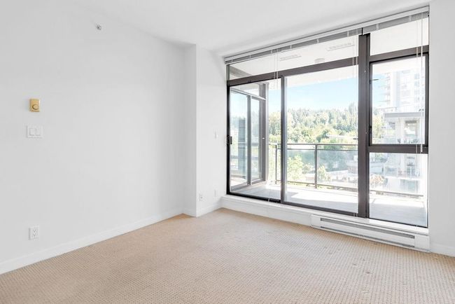 Empty room featuring baseboard heating, light colored carpet, and a wall of windows | Image 13