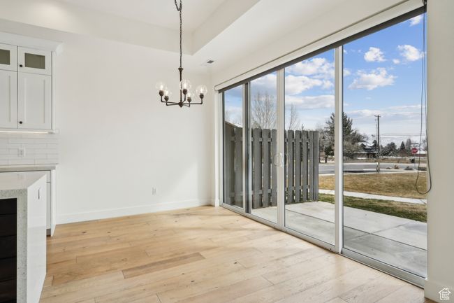 Unfurnished dining area with an inviting chandelier, light wood-style flooring, and baseboards | Image 20