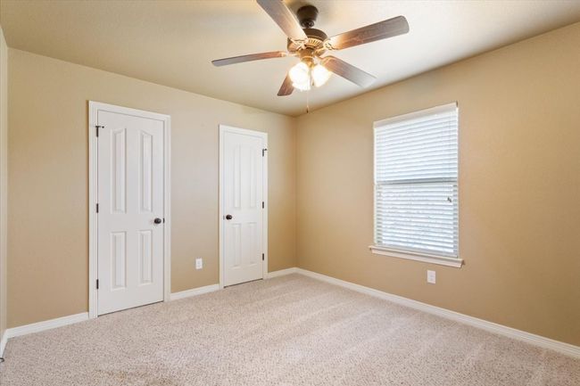 Unfurnished bedroom featuring carpet, baseboards, two closets, and ceiling fan | Image 26