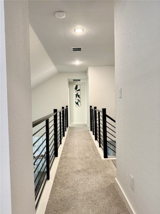 Hall with an upstairs landing, carpet, and a textured wall | Image 8