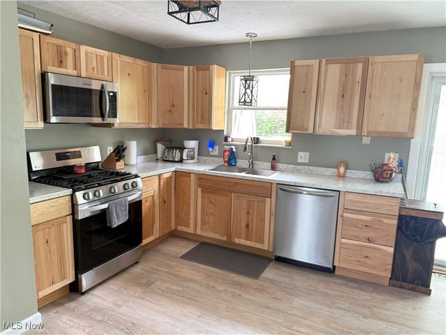 Kitchen with light brown cabinetry, light countertops, a sink, light wood-style flooring, and appliances with stainless steel finishes | Image 8