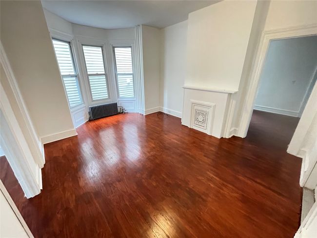Empty room featuring radiator, wood finished floors, and baseboards | Image 4