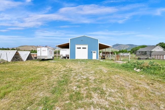 View of yard with a detached garage, a mountain view, an outdoor structure, and an outbuilding | Image 60