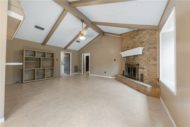 Unfurnished living room featuring tile patterned floors, beam ceiling, ceiling fan, a brick fireplace, and high vaulted ceiling | Image 4