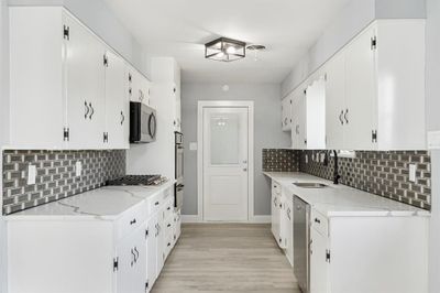 Kitchen featuring white cabinets, light hardwood / wood-style floors, appliances with stainless steel finishes, and sink | Image 3