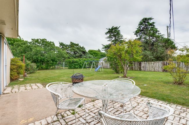 View of patio featuring a fenced backyard, a playground, a fire pit, and outdoor dining space | Image 28