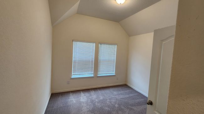 Empty room featuring dark carpet, lofted ceiling, and baseboards | Image 14