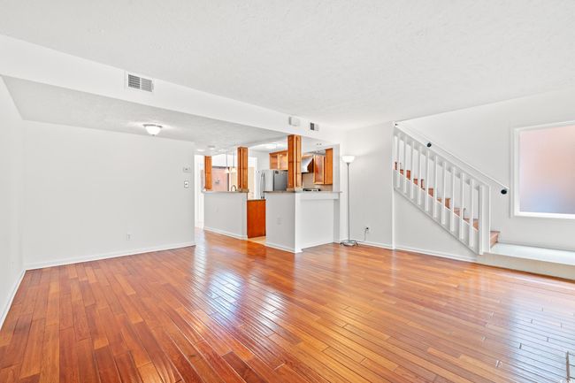 Unfurnished living room with stairway, light wood-style flooring, and a textured ceiling | Image 6