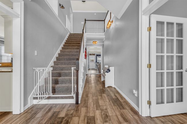 Staircase with ornamental molding, hardwood / wood-style floors, and a high ceiling | Image 19