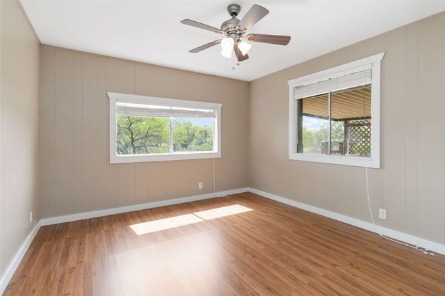 Empty room featuring baseboards, a wealth of natural light, wood finished floors, and a ceiling fan | Image 17