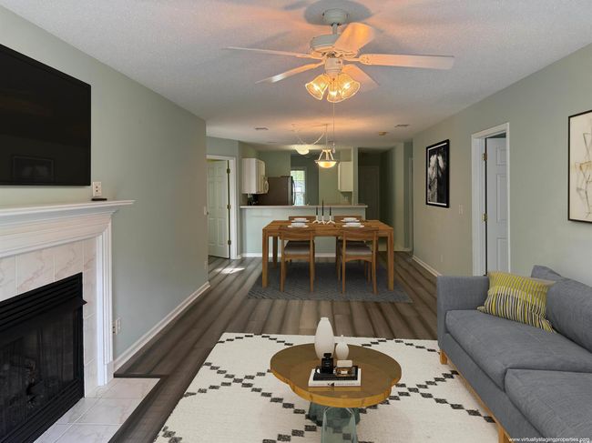 Living room with wood finished floors, a ceiling fan, baseboards, a fireplace, and a textured ceiling | Image 13