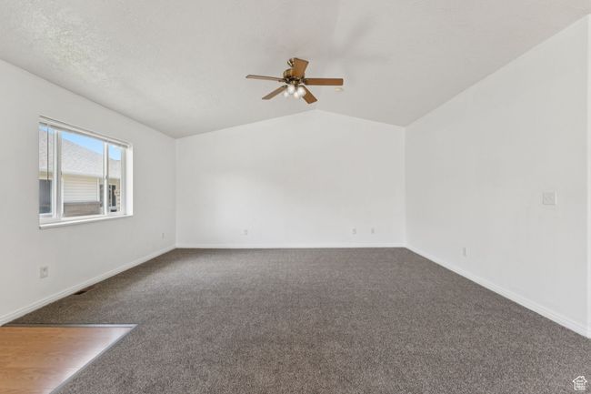 Carpeted empty room with ceiling fan and lofted ceiling | Image 17