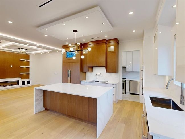 Kitchen featuring a large island, brown cabinetry, light wood-style floors, a chandelier, and recessed lighting | Image 13
