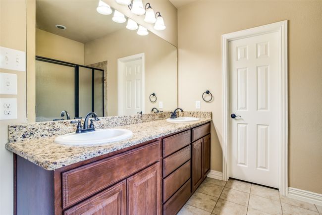 Bathroom with tile patterned flooring, double vanity, a shower stall, and baseboards | Image 11