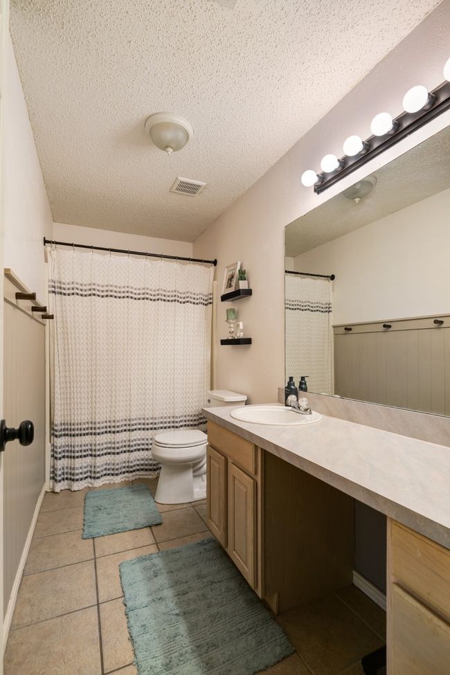 Bathroom with vanity, tile patterned flooring, a textured ceiling, and a shower with shower curtain | Image 14