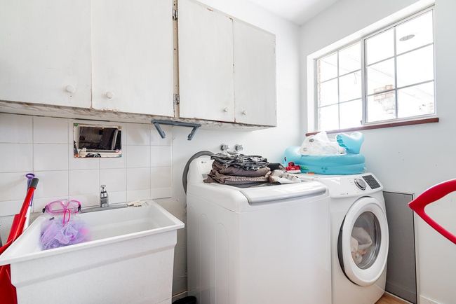 Washroom featuring cabinet space, washing machine and clothes dryer, and a sink | Image 32
