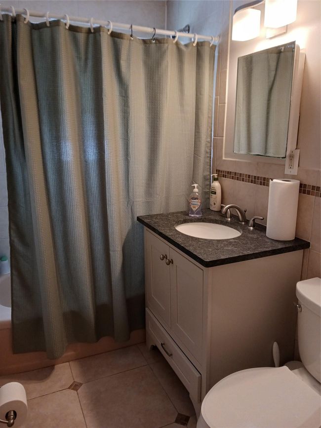 Bathroom featuring tile patterned floors, shower / tub combo with curtain, toilet, and vanity | Image 17