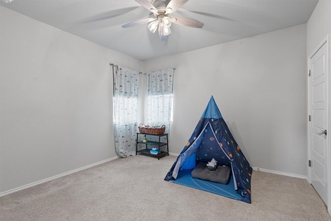 This bedroom includes multiple windows, a ceiling fan, and a walk-in closet. | Image 21