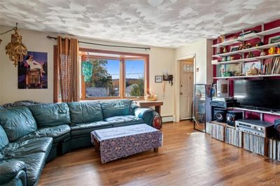 Living room featuring a textured ceiling, a baseboard heating unit, and hardwood / wood-style flooring | Image 2