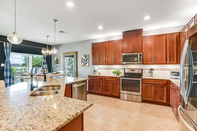 Kitchen with stainless steel appliances, a sink, tasteful backsplash, recessed lighting, and light stone counters | Image 5
