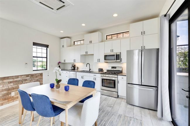 Kitchen featuring stainless steel appliances, dark countertops, light wood-type flooring, white cabinets, and recessed lighting | Image 22