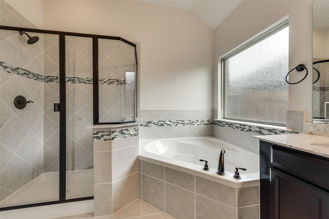 Full bathroom featuring vanity, a stall shower, a bath, and lofted ceiling | Image 13