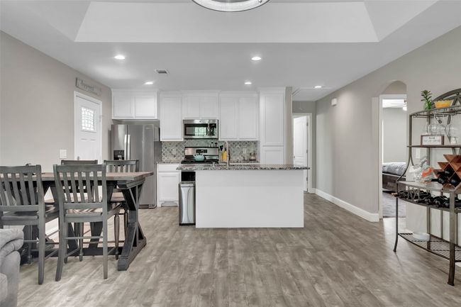 Kitchen with tasteful backsplash, stone counters, white cabinetry, and stainless steel appliances | Image 17